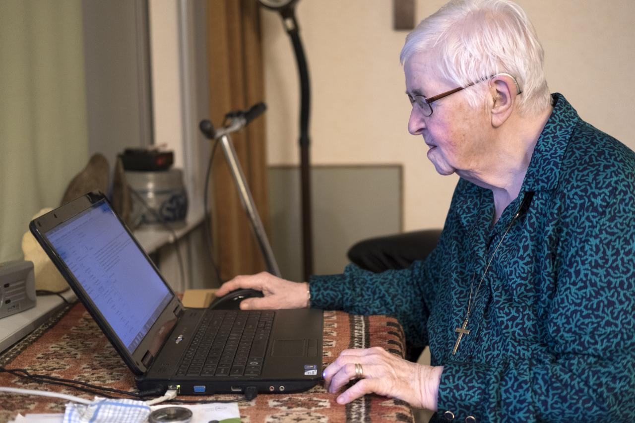 Foto van een oudere vrouw achter de laptop