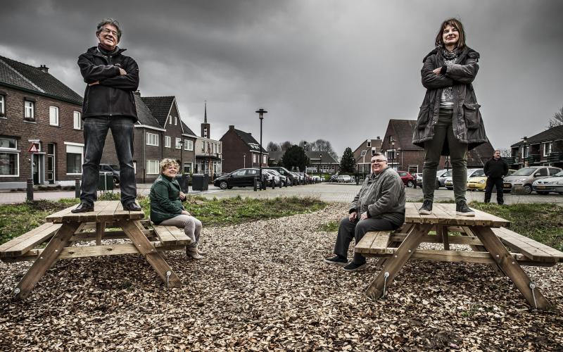 Vier mensen staan trots op tafels in woonwijk bij burgerinitiatief
