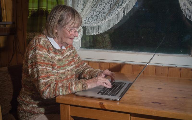 vrouw achter laptop aan keukentafel