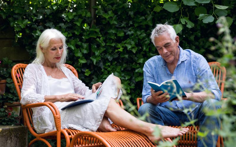 Gepensioneerd echtpaar lezend in de tuin