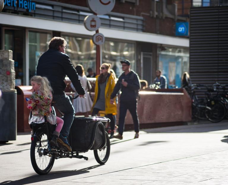 Vader fiets met kind door de straat