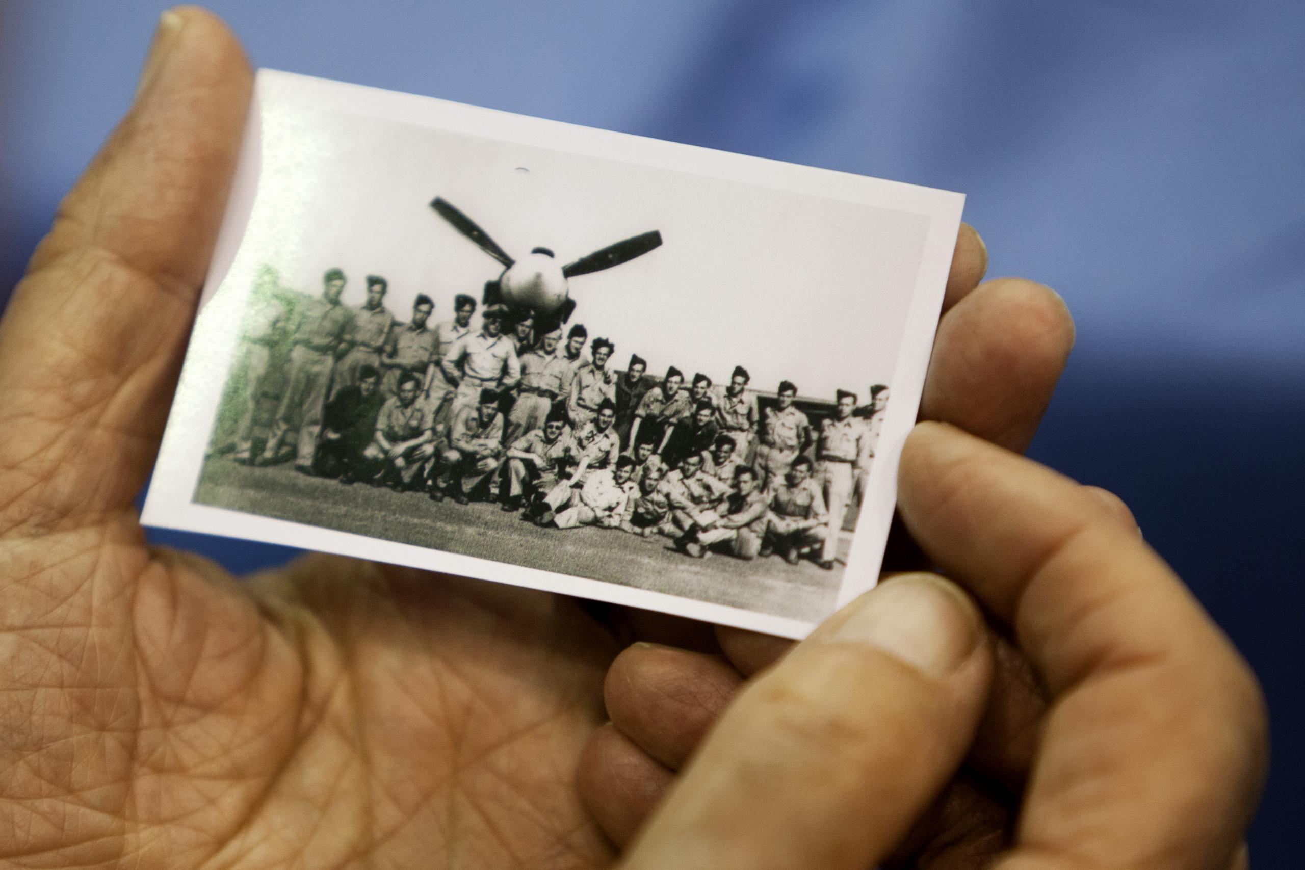 persoon houdt oude foto vast met militairen voor een vliegtuig