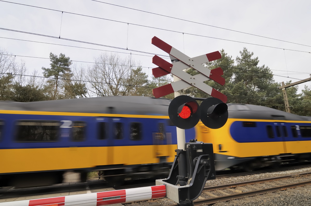 Foto van een spoorwegovergang waar een trein langs komt