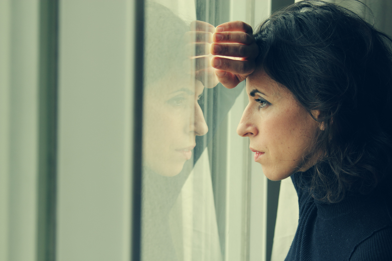 Bezorgde vrouw kijkt uit het raam Bezorgde vrouw kijkt uit het raam