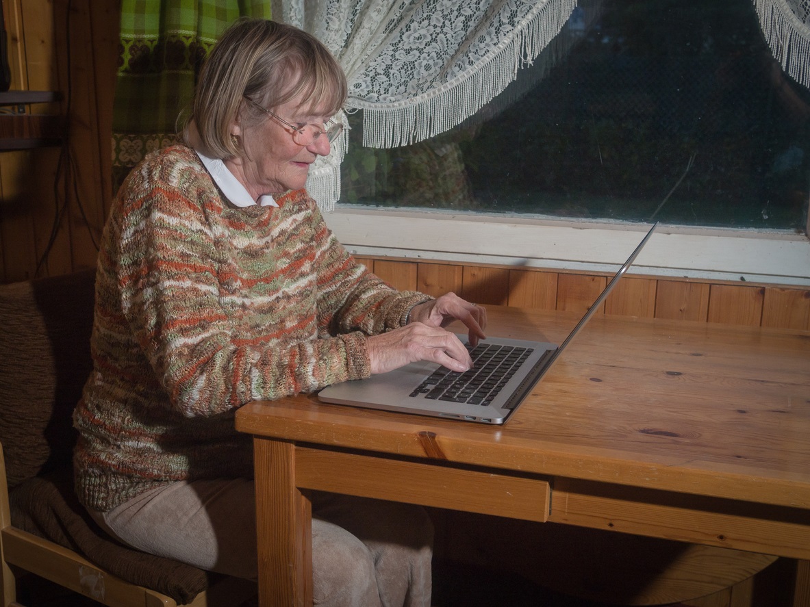 vrouw achter laptop aan keukentafel