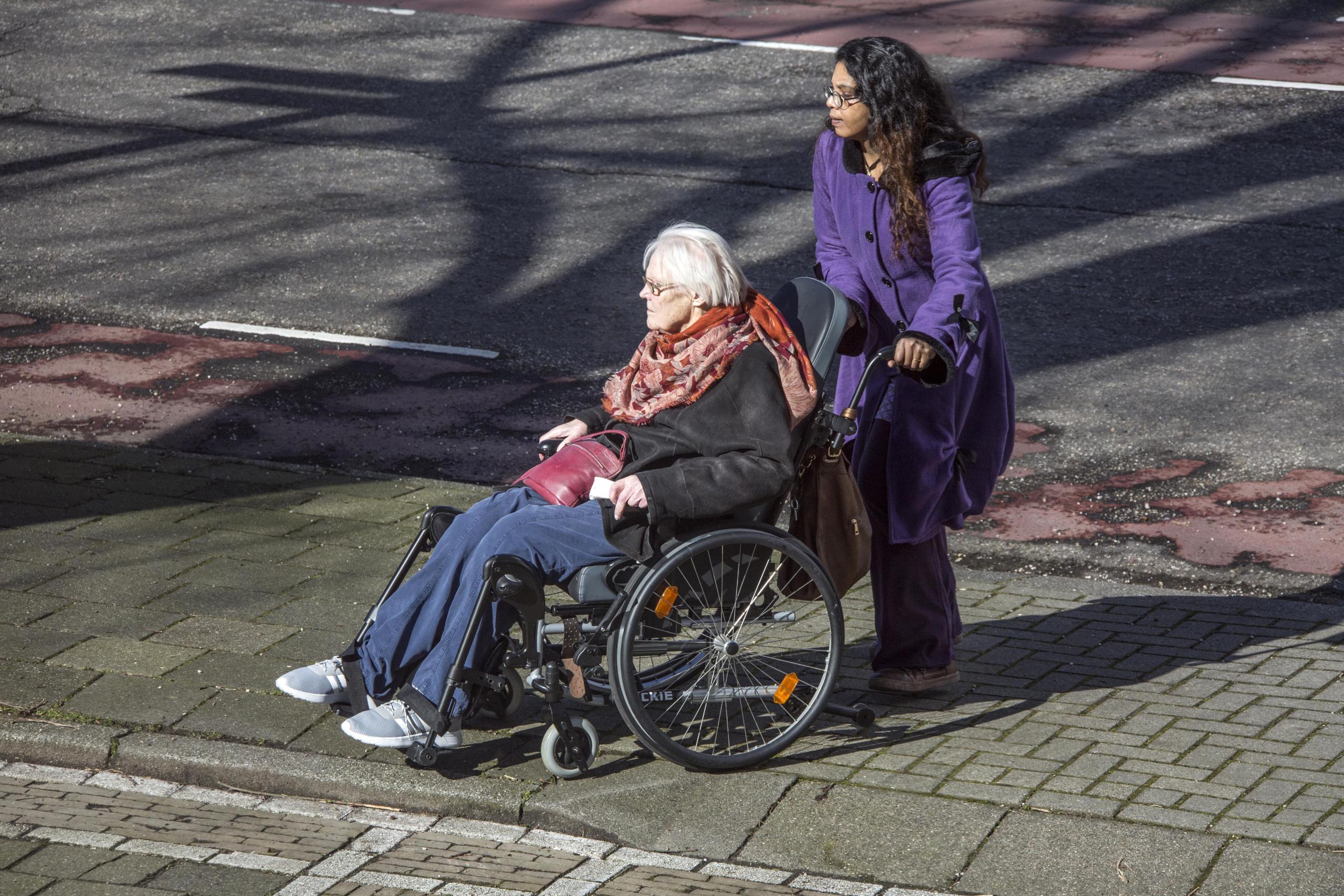 Vrouw in rolstoel wordt rondgereden Vrouw in rolstoel wordt rondgereden
