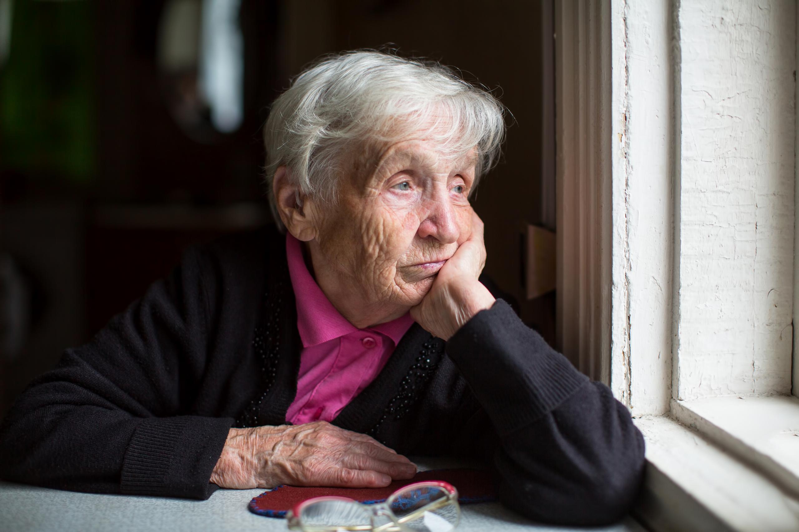 Foto van een oude vrouw die uit het raam kijkt Foto van een oude vrouw die uit het raam kijkt