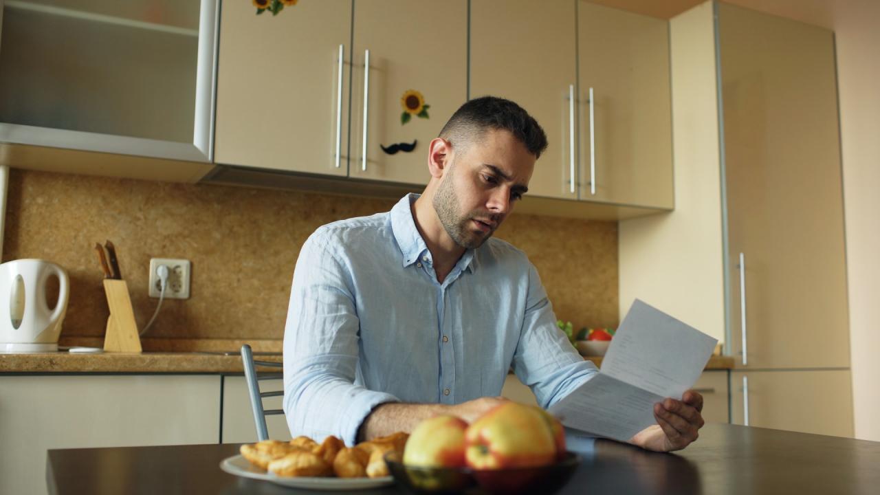 Man leest brief in de keuken