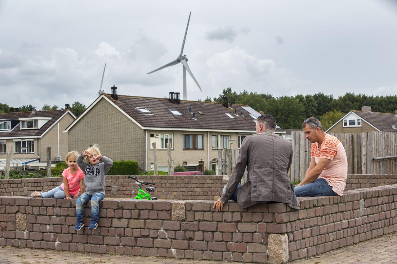 Mannen met hun kinderen en op de achtergrond een windmolen