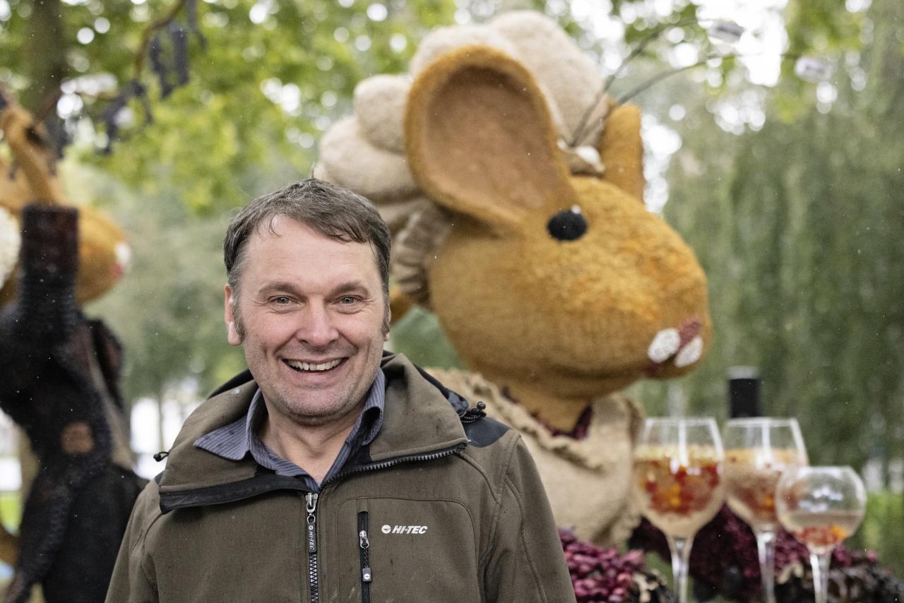 Bert, een man van middelbare leeftijd met een bruine jas aan. Hij staat voor een praalwagen van een konijn