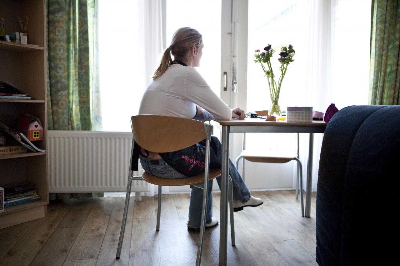 Foto van een vrouw op een stoel kijkend uit het raam