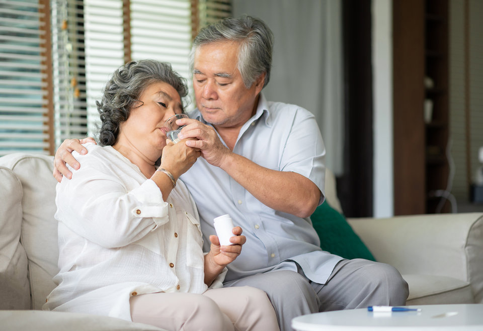 Mantelzorger man helpt zijn vrouw met medicijnen innemen