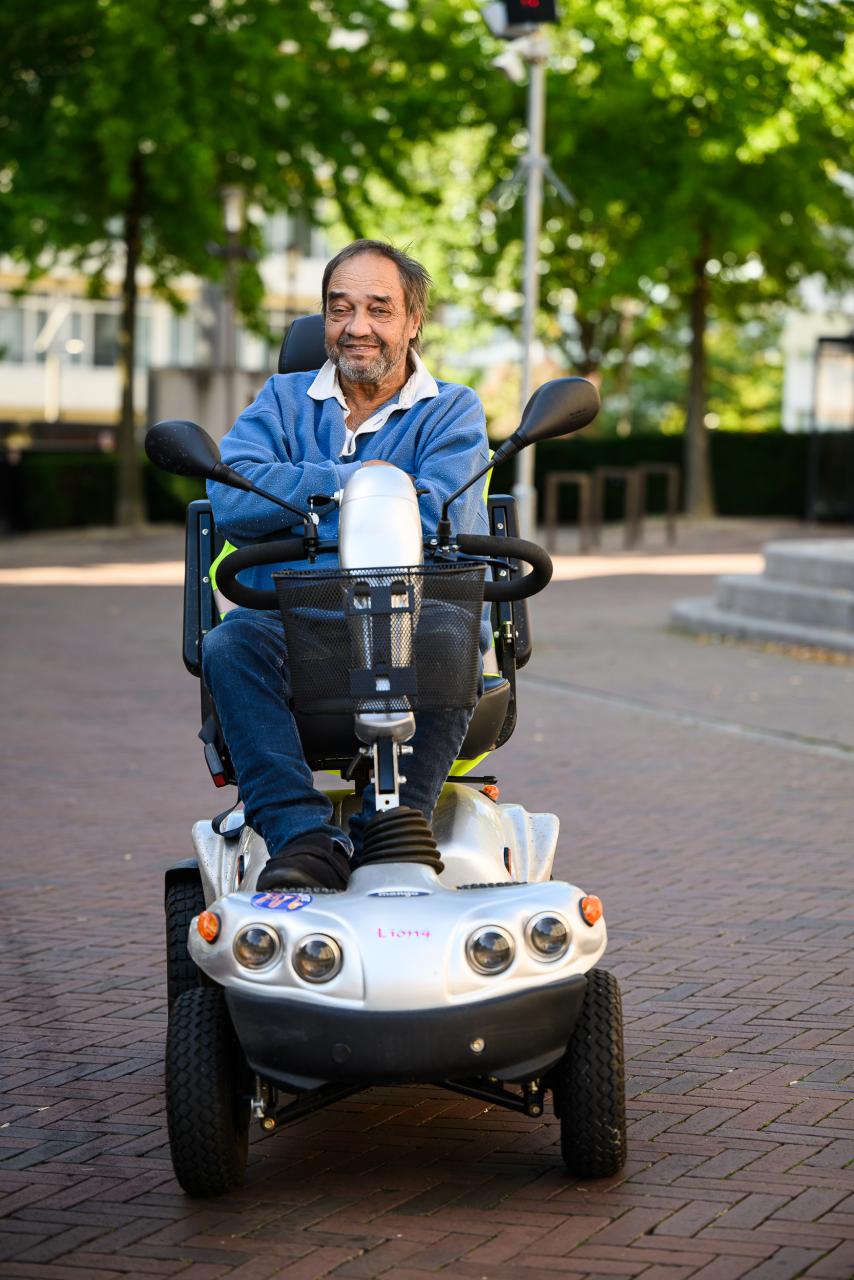 Een glimlachende man op een scootbmobiel