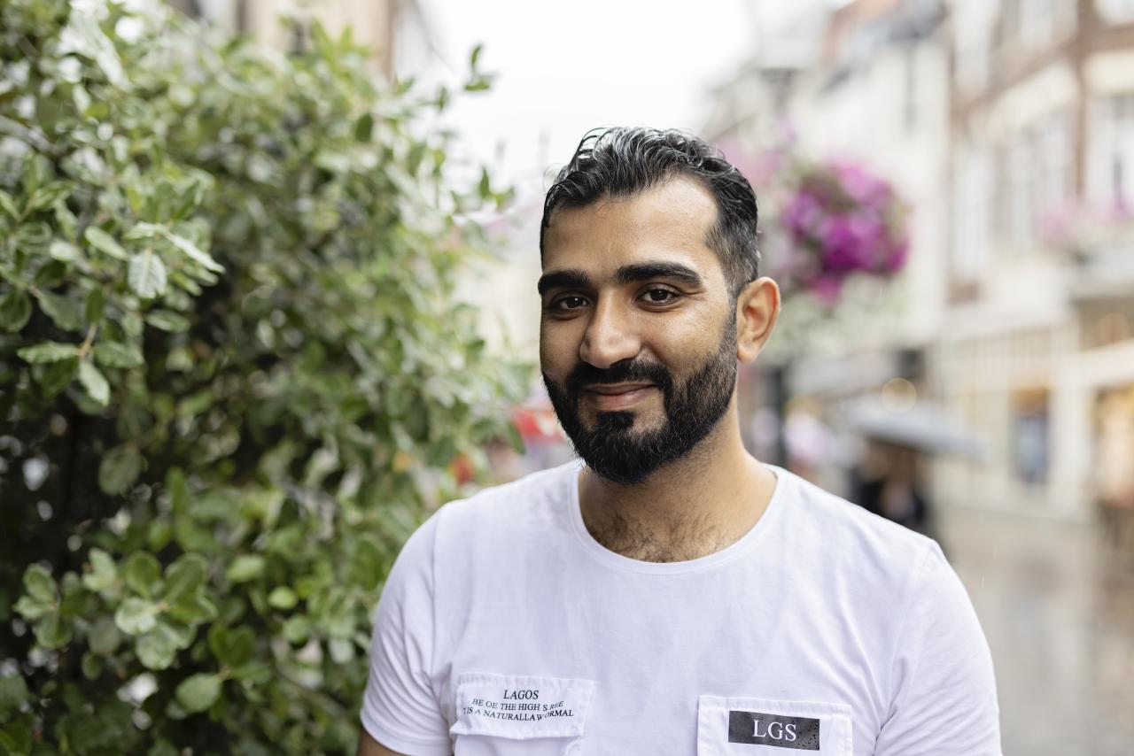 Portret van jongeman met wit t-shirt, zwart haar en zwart baardje.