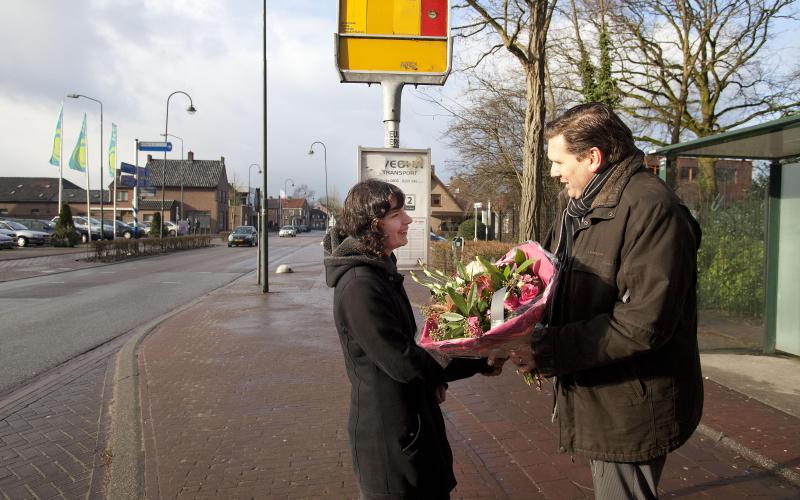 Foto van een man die op straat een bos bloemen geeft aan een vrouw