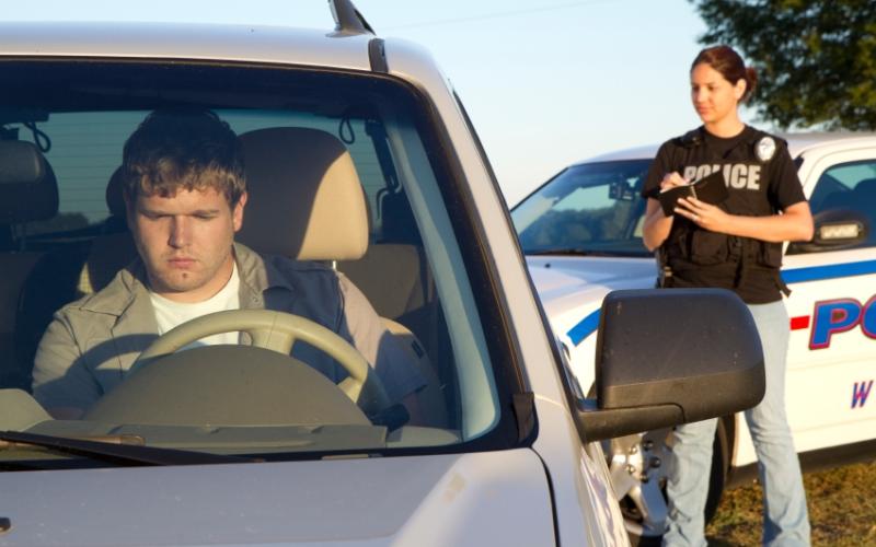 Foto van een agent bij een auto met bestuurder Foto van een agent bij een auto met bestuurder