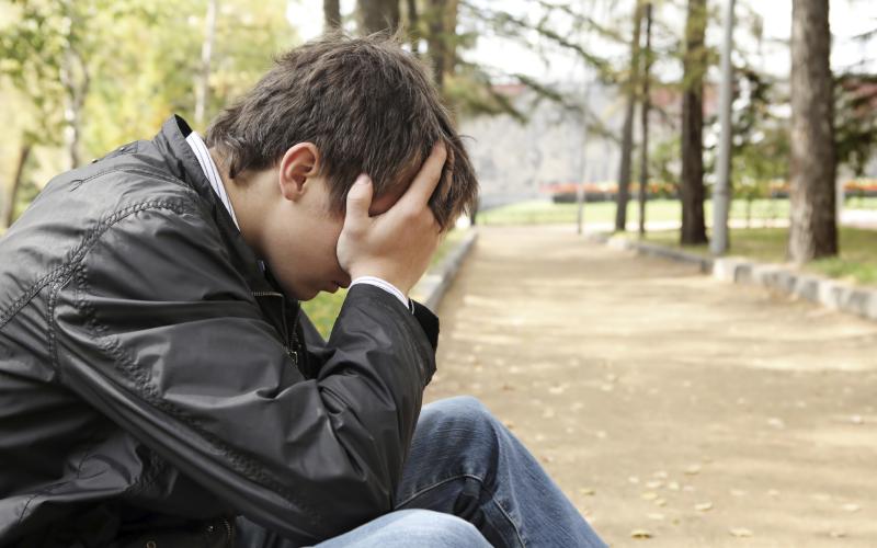 Man met handen in het haar, zittend in een park