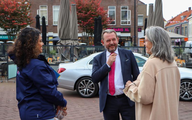 Nationale ombudsman Reinier van Zutphen in gesprek met collega Mira (jonge vrouw met bruin krullend haar) en een vrouw op straat (middelbare leeftijd, grijs haar)