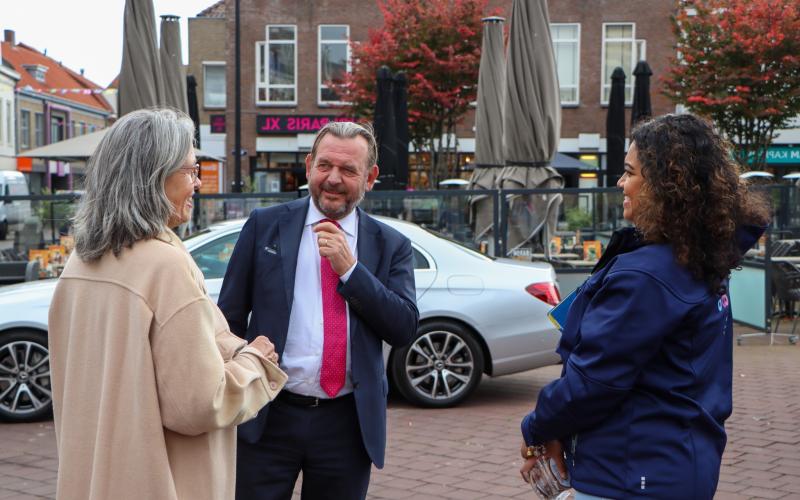 De Nationale ombudsman in gesprek met een vrouw met grijs haar en een beige jas. Links van hen staat een vrouwelijke collega van de ombudsman. De Nationale ombudsman in gesprek met een vrouw met grijs haar en een beige jas. Links van hen staat een vrouwelijke collega van de ombudsman.