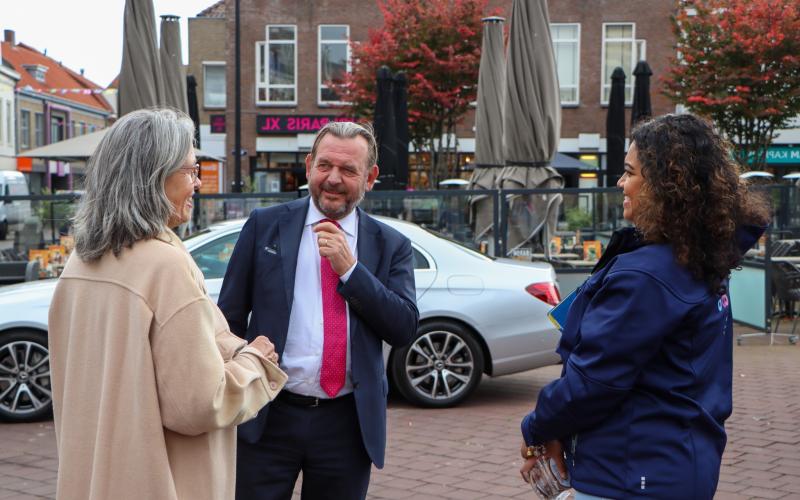 De Nationale ombudsman in gesprek met een vrouw met grijs haar en een beige jas. Links van hen staat een vrouwelijke collega van de ombudsman.