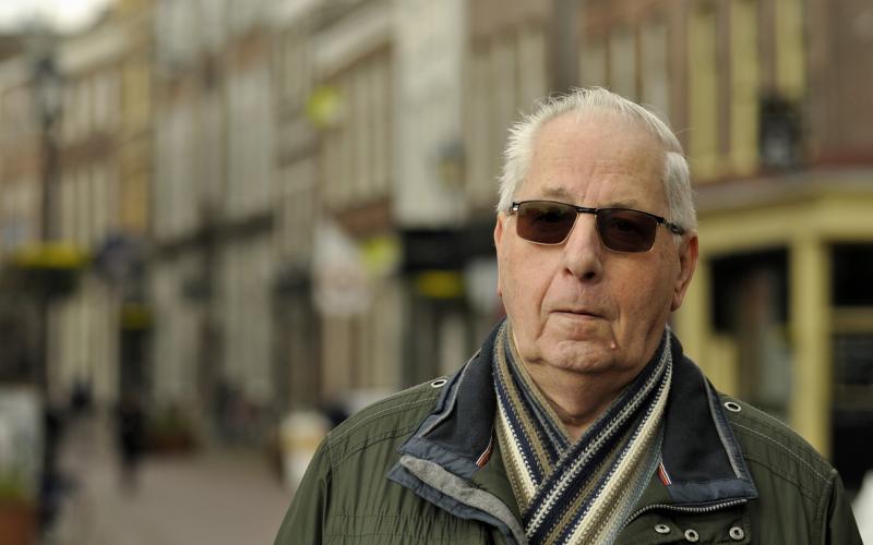 Senior man met zonnebril en sjaal om op straat Senior man met zonnebril en sjaal om op straat