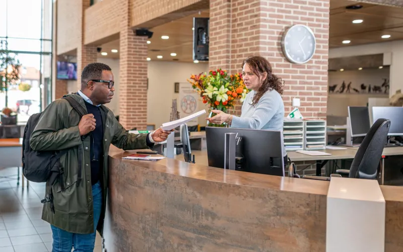 Een man staat bij de balie op het gemeentekantoor