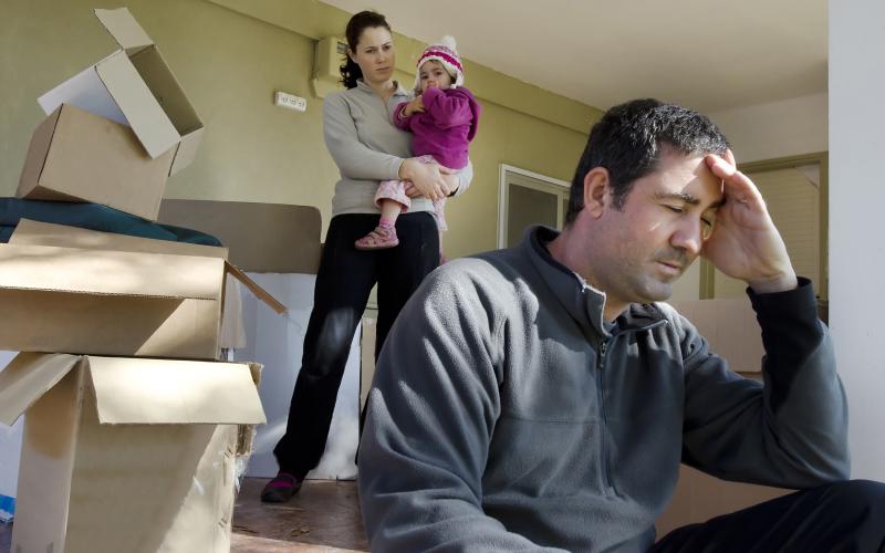 Gezin (man, vrouw en kind) in een leeg huis met verhuisdozen. 