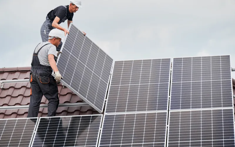 Twee mannen staan op een dak zonnepanelen te monteren