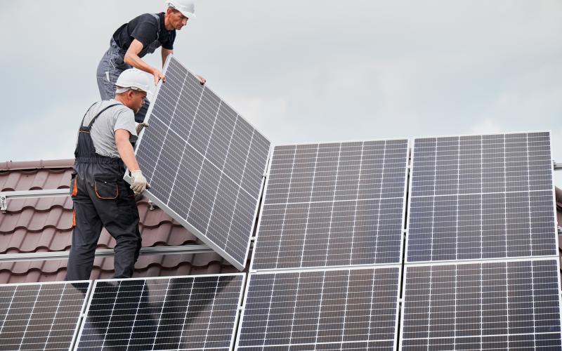 Twee mannen staan op een dak zonnepanelen te monteren