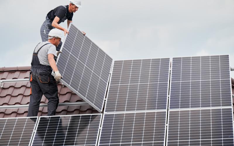 Twee mannen staan op een dak zonnepanelen te monteren Twee mannen staan op een dak zonnepanelen te monteren