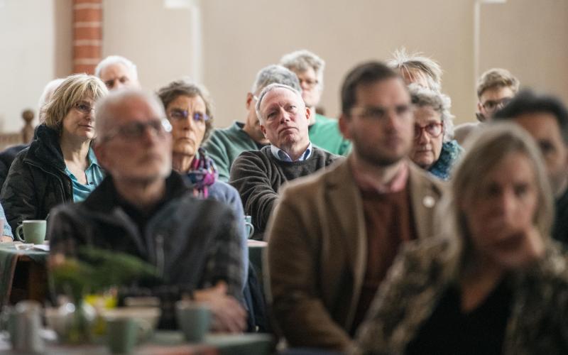 Groep inwoners van Loppersum (Groningen) luistert naar iemand bij een bijeenkomst