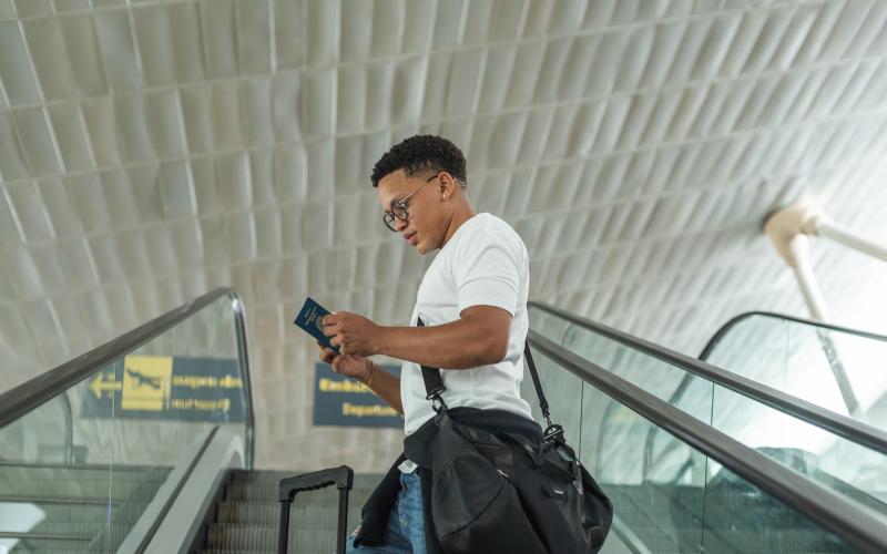 Jonge man op vliegveld kijkt naar paspoort