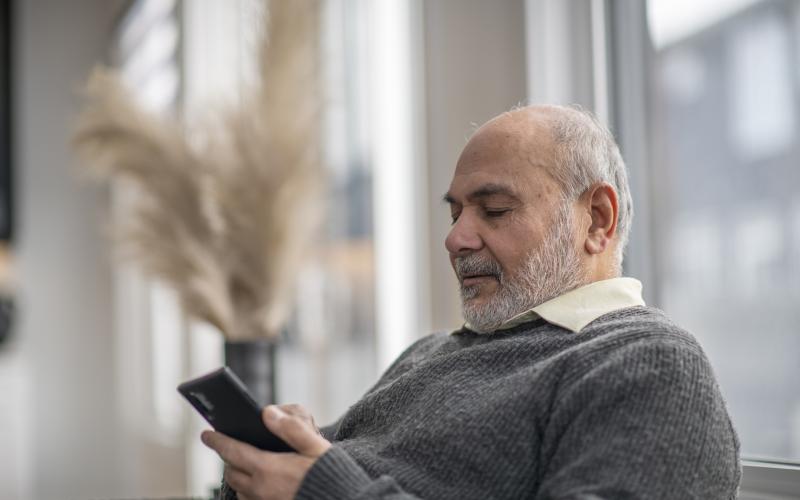 Oudere man op de bank met telefoon Oudere man op de bank met telefoon