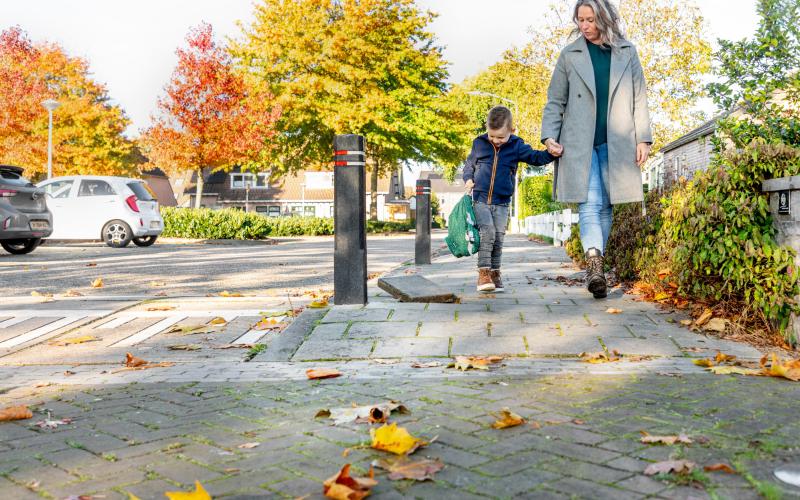 Moeder en zoon lopen op straat. Het jongetje houdt zijn rugzak vast.