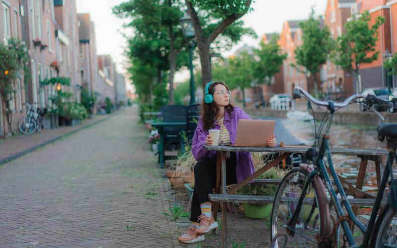 Jonge vrouw zit aan de gracht met een computer