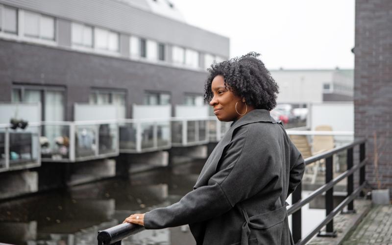 Vrouw van middelbare leeftijd staat bij haar huis aan het water Vrouw van middelbare leeftijd staat bij haar huis aan het water