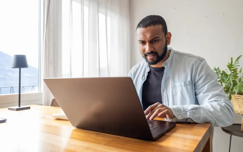 Jongvolwassen man zit achter zijn laptop