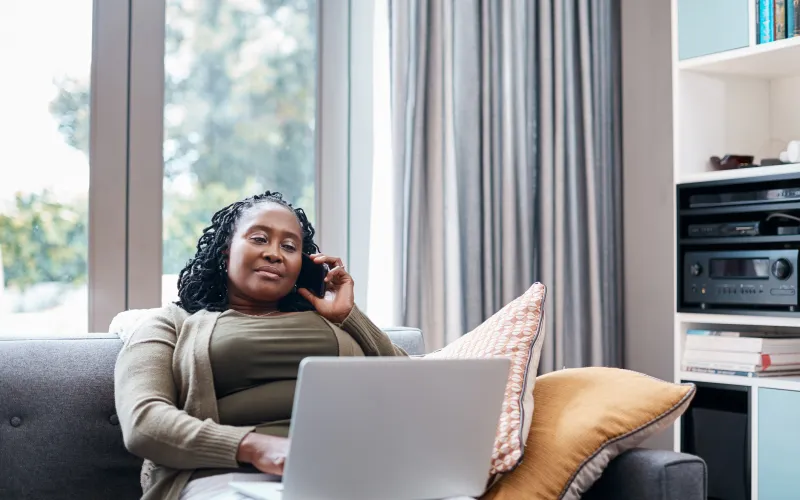 Vrouw zit op de bank met laptop op schoot