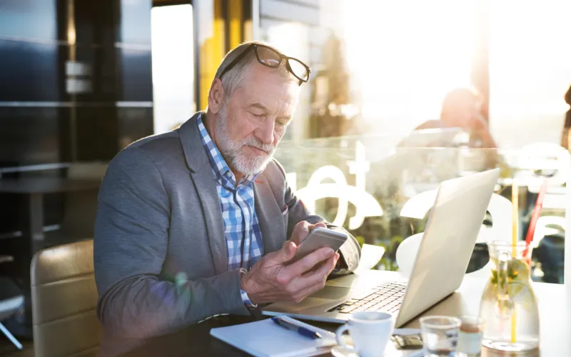Senior man zit te werken en achter zijn laptop