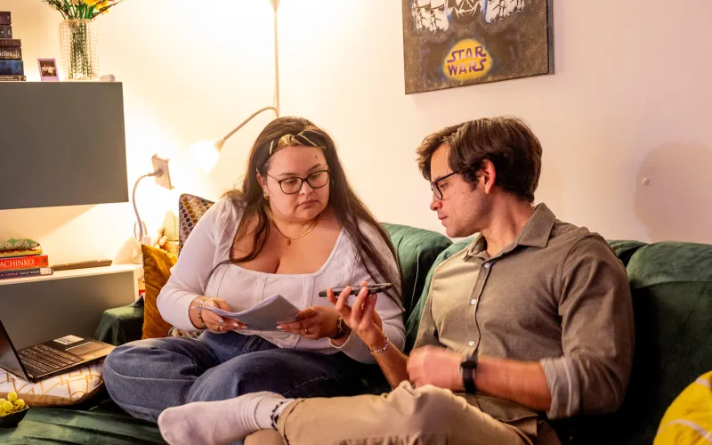 Jong stel zit thuis op de bank met papieren in de hand