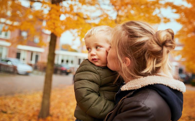 Moeder heeft zoon vast en staan op straat in de herfst