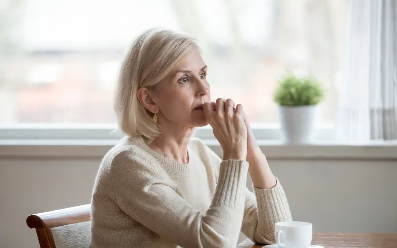 Senior vrouw kijkt bedenkelijk voor zich uit