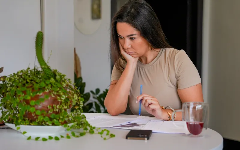 Vrouw op Bonaire zit met papieren voor zich en kijkt ontevreden