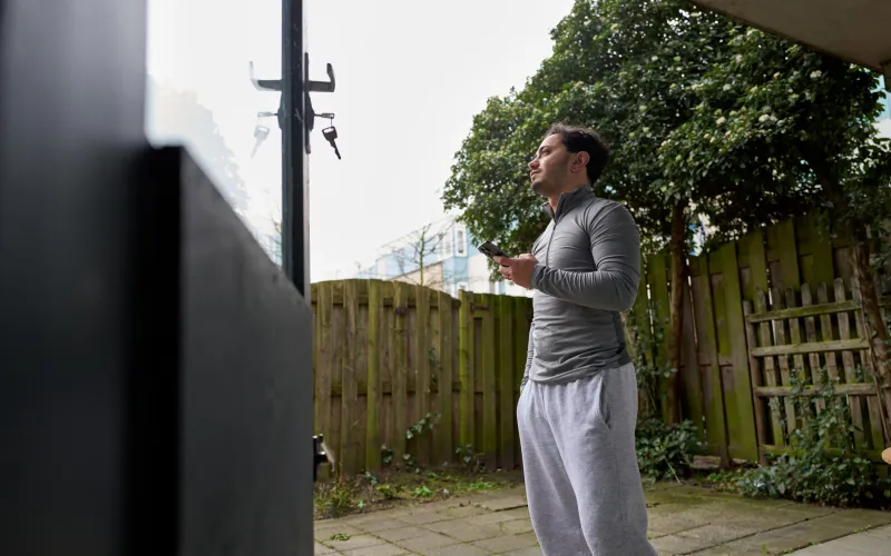 Jongeman staat in de tuin met een telefoon in zijn hand