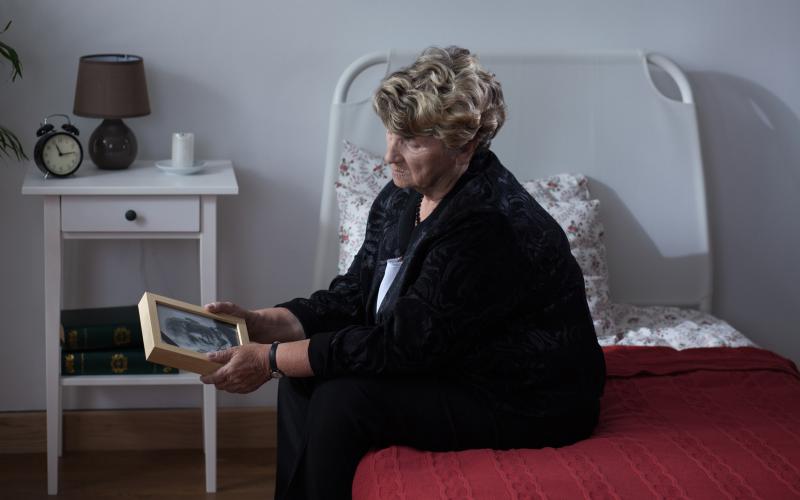 Vrouw met portret van overleden man in haar hand