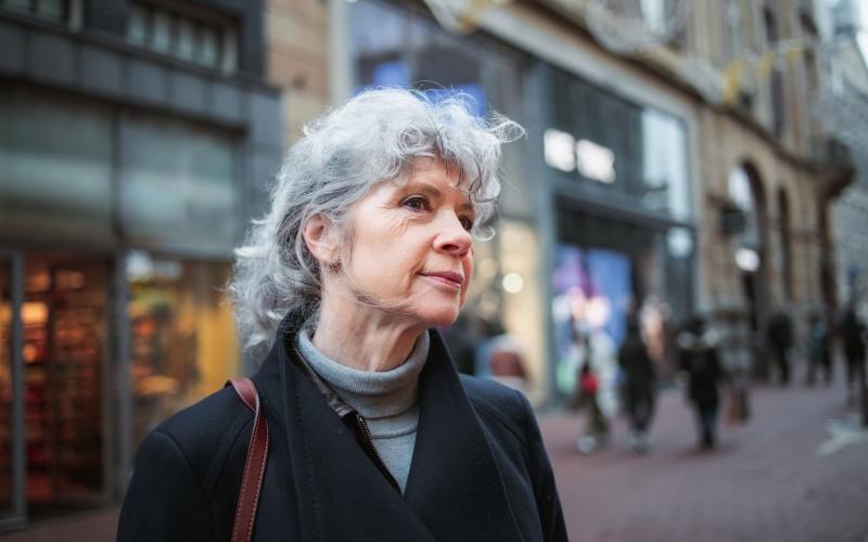 Oudere vrouw staat in een winkelstraat