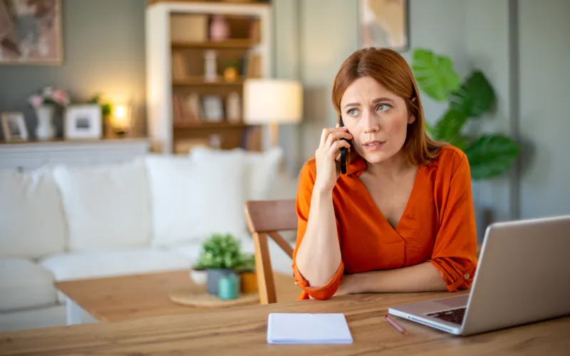 Vrouw aan telefoon achter laptop
