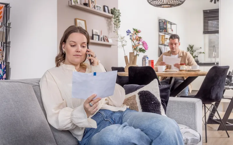 vrouw met brief in hand aan de telefoon