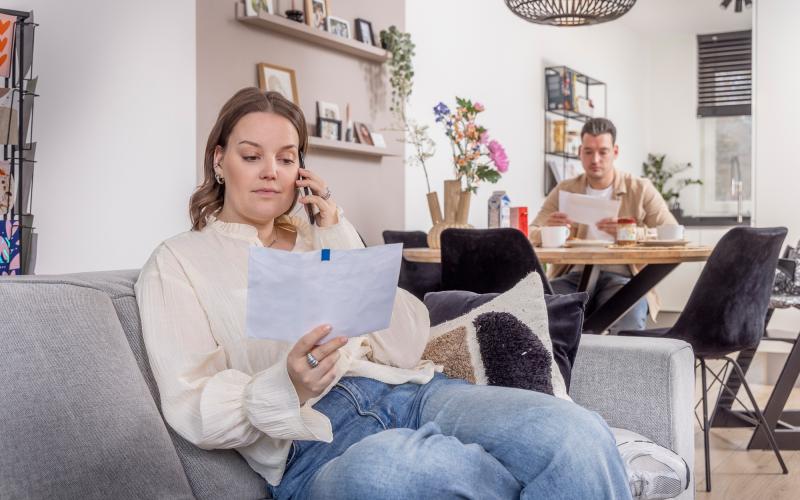 vrouw met brief in hand aan de telefoon