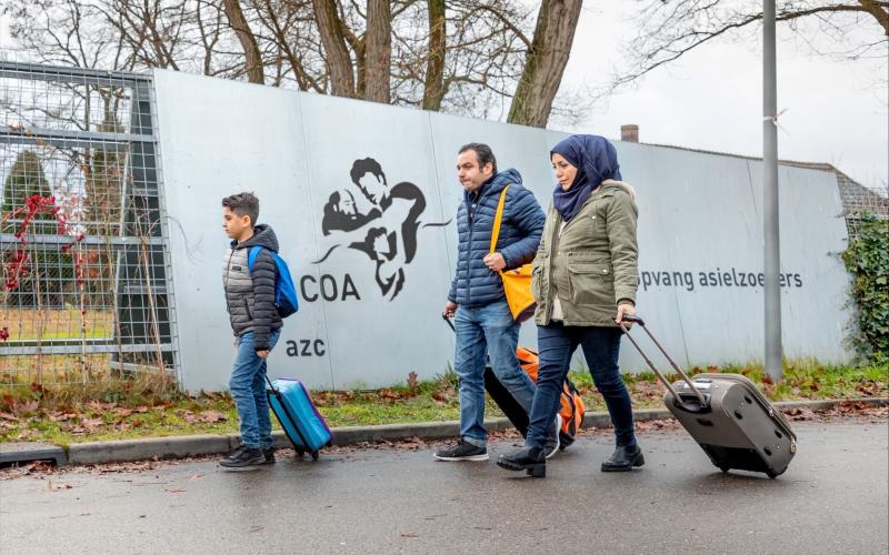 Azielzoekers (man, vrouw, kind) lopen naar AZC